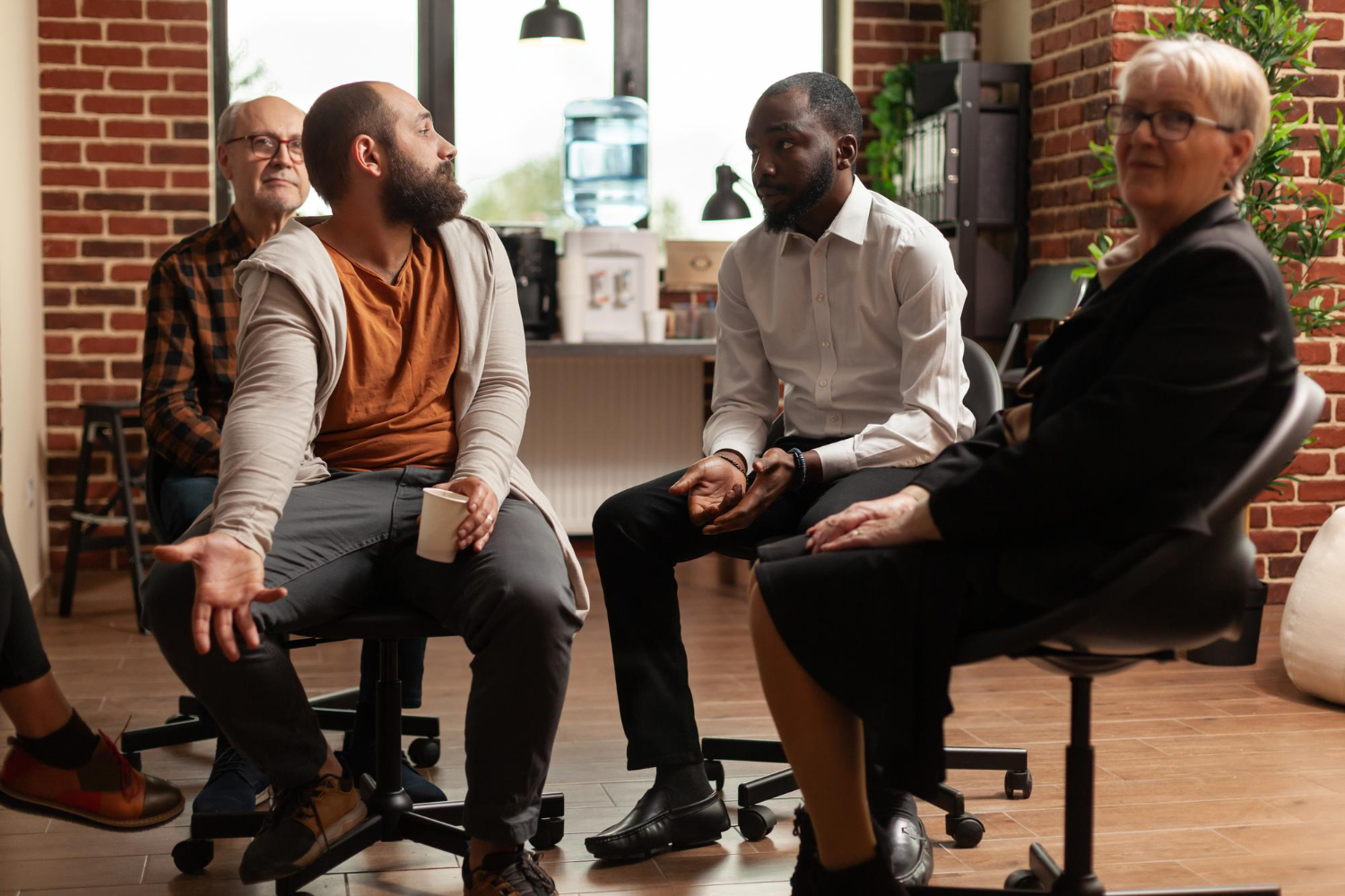 multi-ethnic-group-of-people-at-aa-therapy-meeting-talking-together-patients-with-alcohol-addiction-having-conversation-about-mental-health-problems-and-recovery-while-sitting-in-circle (1)
